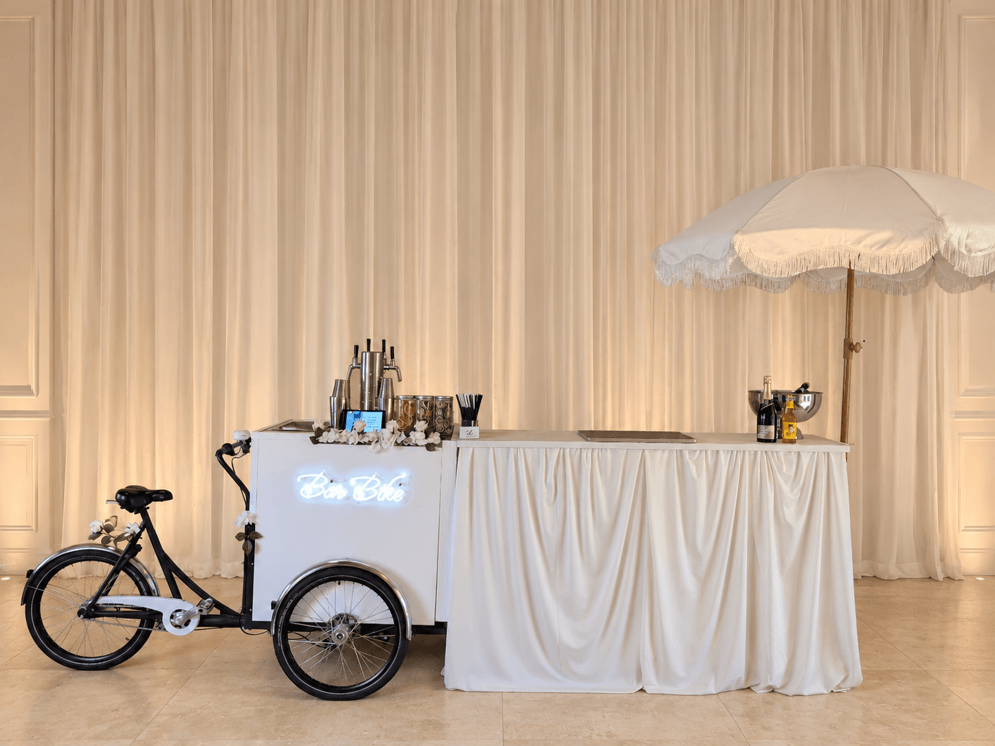 BarBike cocktail tricycle beside the white-draped Essentials Bar